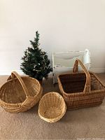 Wide shot showing all items together: three woven baskets, wooden magazine rack, and small decorated Christmas tree on carpet