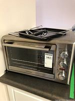 Front angle of stainless steel Hamilton Beach countertop oven with glass door and removable racks on top