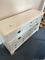Photo of the white solid wood dresser showing wear and metal handles, angled view from top side.