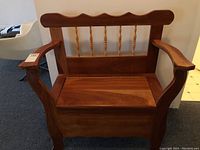 Front view of wooden hall bench showing curved armrests and decorative turned spindle backrest.