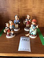 Four Hummel figurines displayed, showing each figurine's detail and relative size.