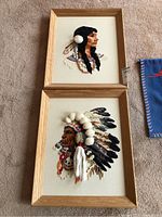 Both framed textile portraits of Indigenous persons displayed on carpet