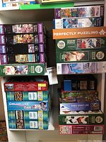 Photo showing stacked puzzle boxes including 2000-piece and 1500-piece puzzles from various brands and themes.