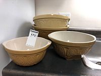 Four mixing bowls stacked and arranged, showing decorative embossed patterns and gripstand base.
