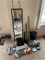 Wide shot of all items: mirror, wrapping paper rolls, shredder, boxes with office supplies, Apple keyboard, power cords, lamp, Sony Walkman, and other miscellaneous items spread on floor.