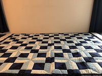 Full view of quilt laid flat against a beige wall