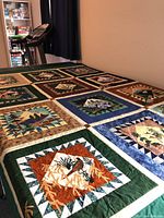 Full view of quilt on table showing grid of nine appliqué nature blocks and solid green sashing.