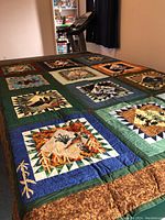 Full view of quilt laid out on table showing patchwork nature scenes