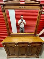 Front view of antique dresser with mirror reflecting a man taking the photo.