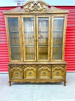 Full front view of the antique hutch showing ornate carved top, four glass-paneled upper doors with chicken wire mesh, and four carved lower drawers.