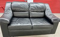 Front view of black leather loveseat sofa showing seat cushions and armrests