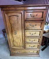 Front view of the burl wood highboy dresser showing six drawers and side cabinet with closed door.