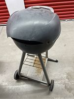 Full view of the electric Char-Broil BBQ grill with closed lid, showing round black hood, handle, and lower shelf with rust.