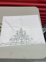 White hand-embroidered pillowcase with gray floral embroidery and scalloped edge
