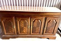 Front view of solid wood buffet with paneled doors and brass handles and removable marble top