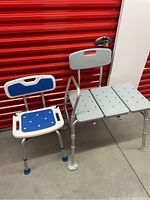 Two medical bath chairs shown side by side against red door background: smaller blue/white chair and larger grey 3-panel chair.