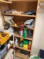 Shelf with garden and cleaning supplies including brushes, spray bottles, garden chemicals, a level, and various small hardware items.