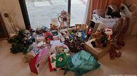 Wide view of multiple Christmas decoration items on floor including figurines, wreaths, garlands, and various boxed ornaments along a sliding door.