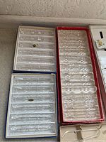 Boxed clear glass utensil rests with multiple slots for knives and forks, showing intricate cut patterns