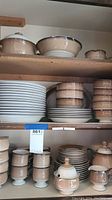 Multiple shelves holding stacks of plates, bowls, cups, and covered sugar bowl, showing overall set and condition with some minor chips