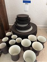Full lot arranged showing stacked plates of various sizes and several cups with handles in front.