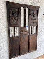 Full front view of mid century dark wood wall decor hanging on a white stucco wall. Shows the overall design and condition.
