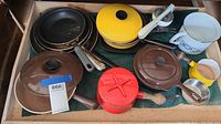 Drawer with assorted pots and pans, showing yellow and red enameled pots, brown casseroles, white floral pot, and small yellow pan