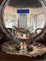 Silver-plated gravy boat with attached decorative underplate showing surface scratches and tarnish.