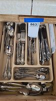 Drawer with assorted Oneida silverware including forks, spoons, and knives with floral embossed handles