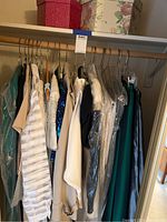 Closet rod with multiple vintage women's dresses and clothing items.