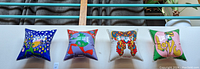 Four mounted square pillows displayed side by side on wall