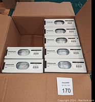 Open cardboard box with seven boxed white filament spools