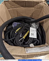 View of the full box containing the coiled black 3/4 inch industrial bungee cord, miscellaneous ropes, and some wrapped parts.