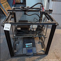Front view of the Creality Ender 5 Plus 3D printer showing the build plate, frame, wiring, and print bed with accessories on it.