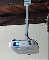 Projector mounted on ceiling bracket powered on