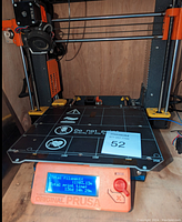 Full front view of printer on wooden shelf with textured carbon fiber plate installed