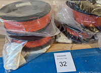 Multiple spools of orange nylon filament in plastic wrap on a table.