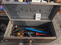 Opened metal toolbox with various hand tools inside including wrenches, pliers, and screwdrivers.