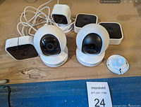 Six used web cameras including two white dome Reolink security cameras with bases and four smaller black and white rectangular cameras. One white mounting bracket also visible.
