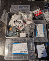 Overview of assorted screws and fasteners in organized plastic boxes and bags on a wooden surface