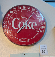 Photo of a red Coca-Cola wall thermometer with 'Enjoy Coke' logo, showing temperature approximately 60 degrees Fahrenheit.