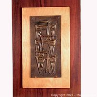 Full front view of bronze relief plaque mounted on wood