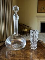 Full view of vintage crystal decanter with faceted stopper and matching tumbler on a tray in a living room setting.