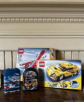 Photo showing LEGO Creator red stunt plane set box 4952, yellow car model 3-in-1 set box 4933, and two small LEGO carry cases