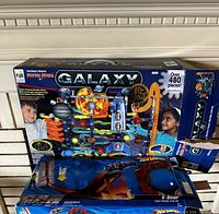 Photo of the boxed Techno Gears Galaxy Marble Mania marble run and Hot Wheels V-Drop track set showing front box art and items included.