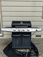 Front view of black Mission gas grill with four control knobs and two-door storage under the grill area.