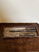 Three-piece sterling silver carving set in fabric-lined box placed on wooden surface.