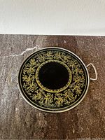 Top-down view of the vintage art deco tray showing black base with gold ornate pattern.