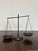 Front view of the vintage brass balance scale with two pans on chains.