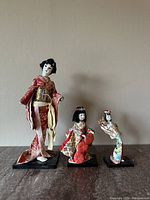 Four vintage Geisha figurines in traditional Japanese attire on black bases